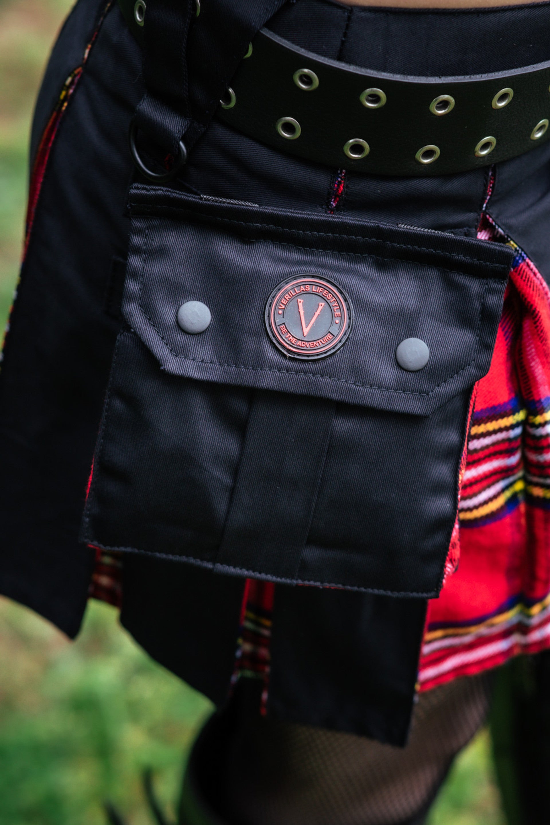 Close up of the pocket detail on a black and red plaid mini kilt featuring the Versatta Kilts logo.