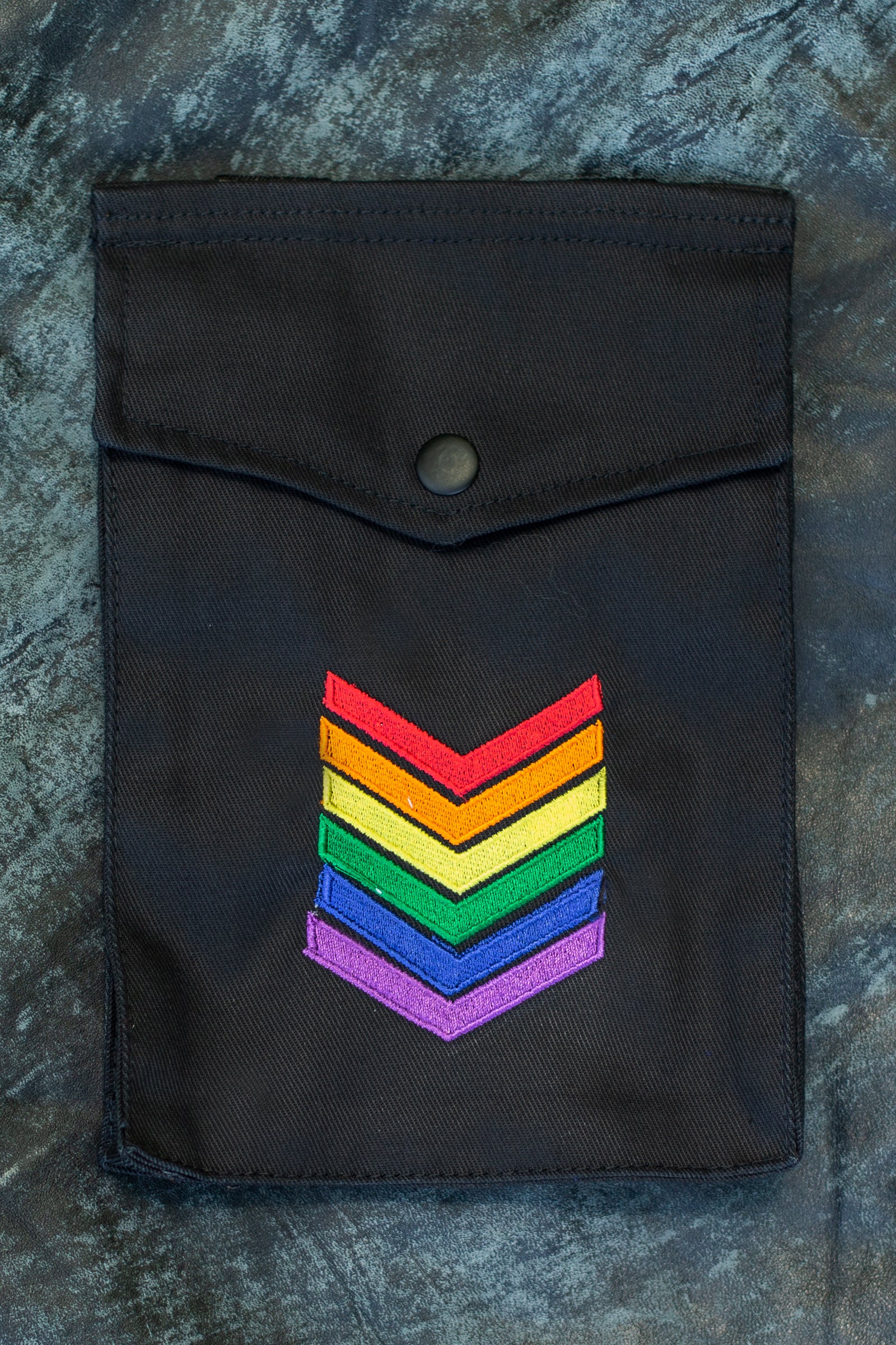 Black pouch with rainbow chevron design on a textured surface.
