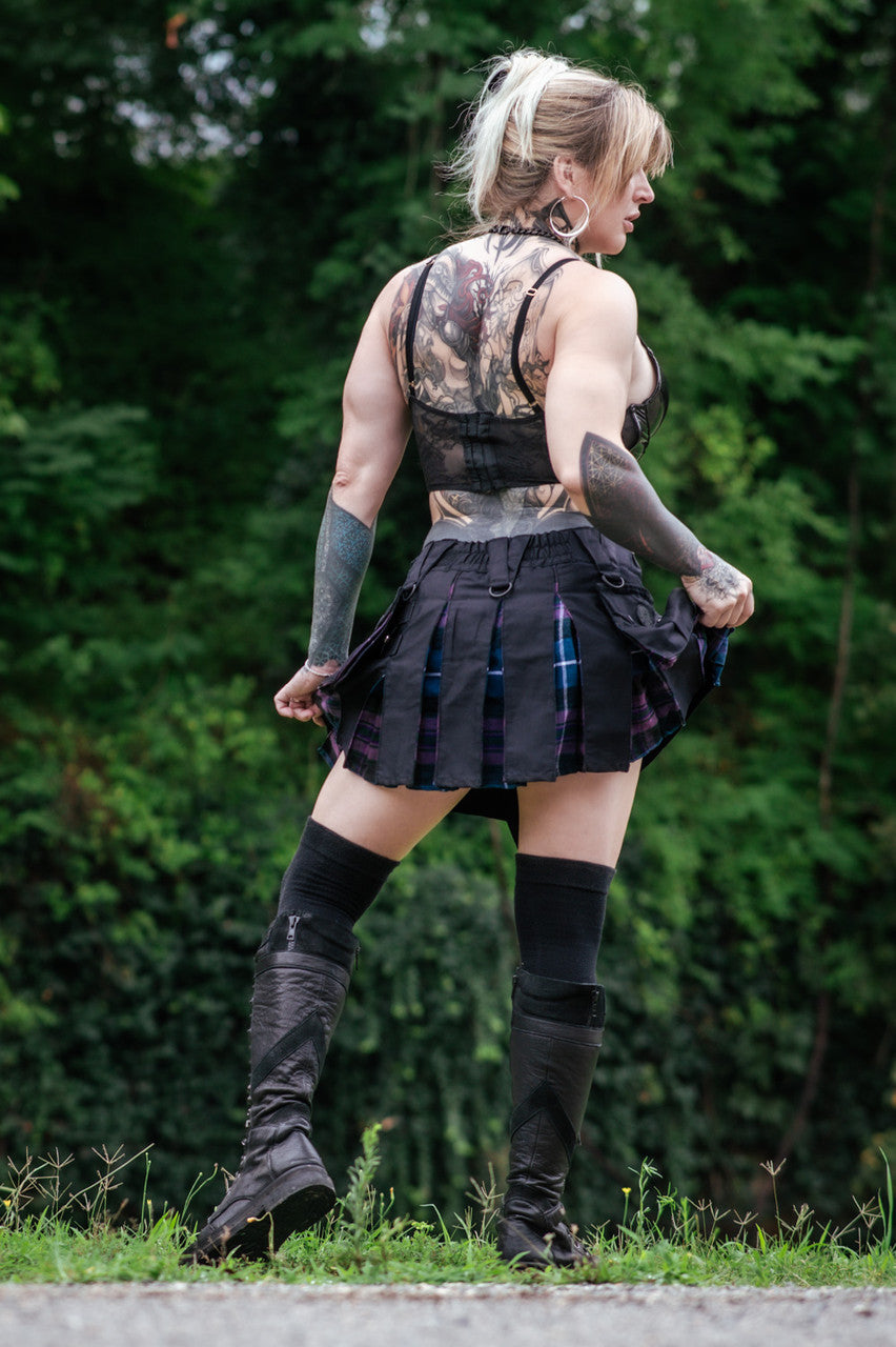 Back view of a woman wearing a black mini kilt with purple and blue plaid details.