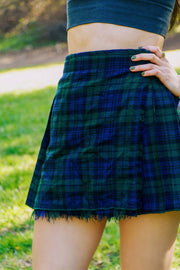 Person wearing a blue and green plaid kilt outdoors on grass