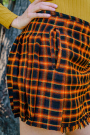 Orange and black plaid mini kilt worn by a person in a nature setting