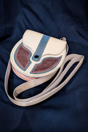 Small trans pride white leather sporran with pink and blue details on a blue cloth background