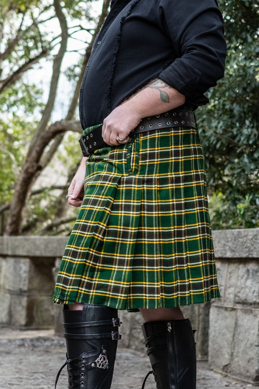 Person wearing a green plaid kilt with black boots in an outdoor setting
