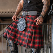 Person wearing a red and black plaid kilt with black boots indoors.