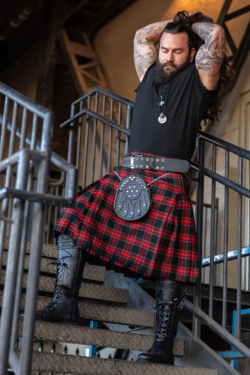 Man wearing a red tartan kilt and black boots on a staircase.