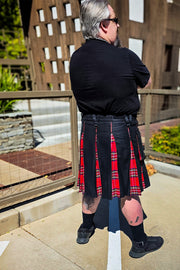 Back view of a person wearing a black and red plaid kilt standing outdoors.