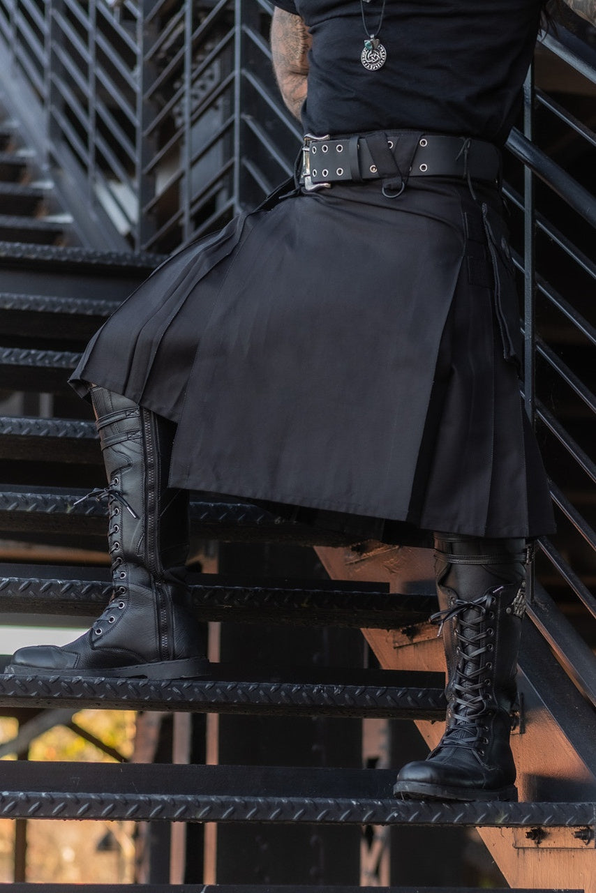 Person wearing a black kilt and boots on metal stairs