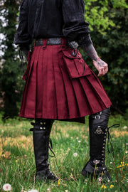 Person wearing a burgundy kilt and black boots in a natural setting