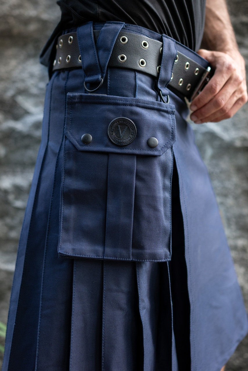 Navy blue kilt with a belt featuring metal buckles against a stone wall background