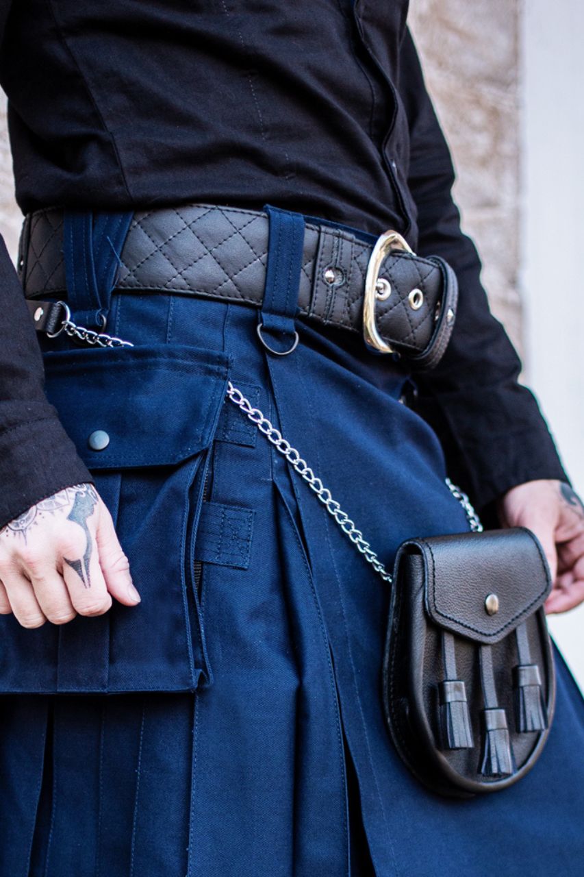 Person wearing a blue kilt with a black belt and pouch, standing against a neutral background.
