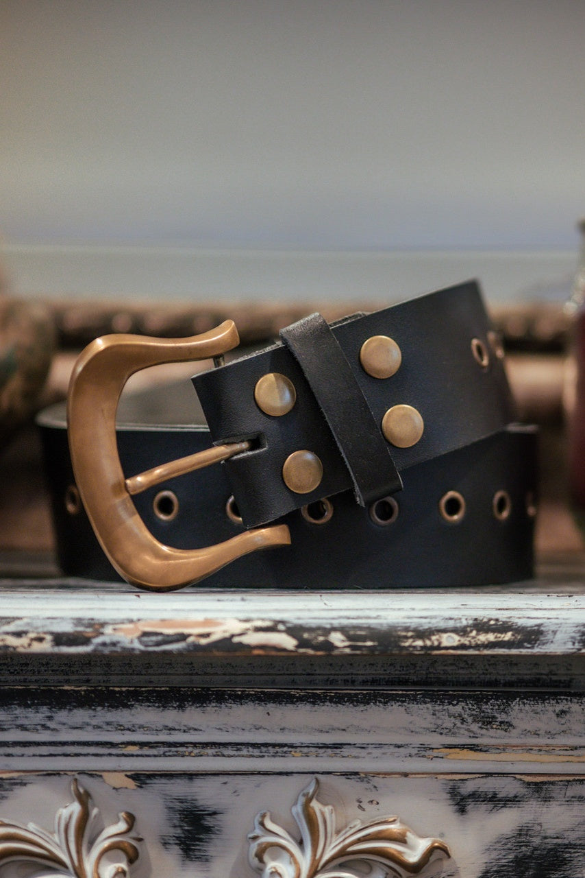 Dark Brown leather belt with a brass.dark gold buckle on a decorative surface