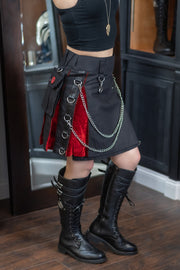 Person wearing a black and red outfit with chains in an indoor setting