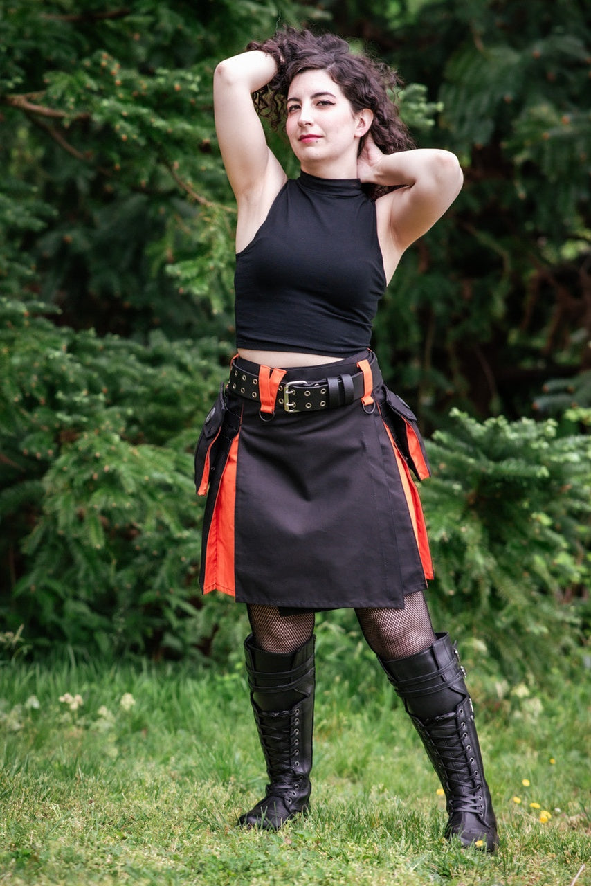Person wearing a black kilt with orange accents outdoors