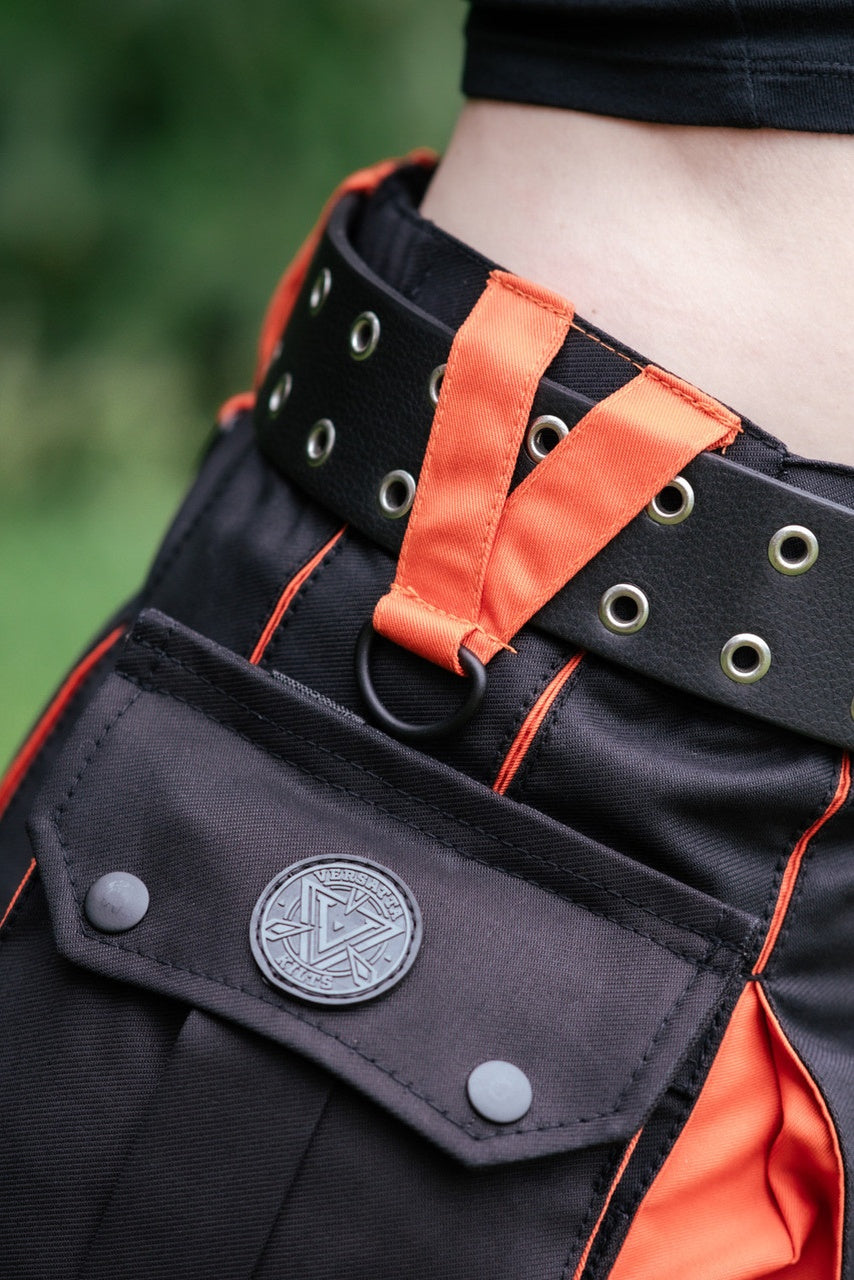 Black and orange belt with a visible brand logo against a blurred green background