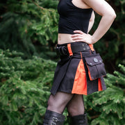 Person wearing a black and orange kilt with a utility belt, standing outdoors.