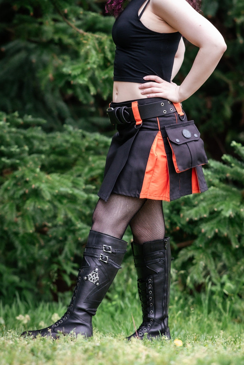 Person wearing a black and orange kilt with a utility belt, standing outdoors.
