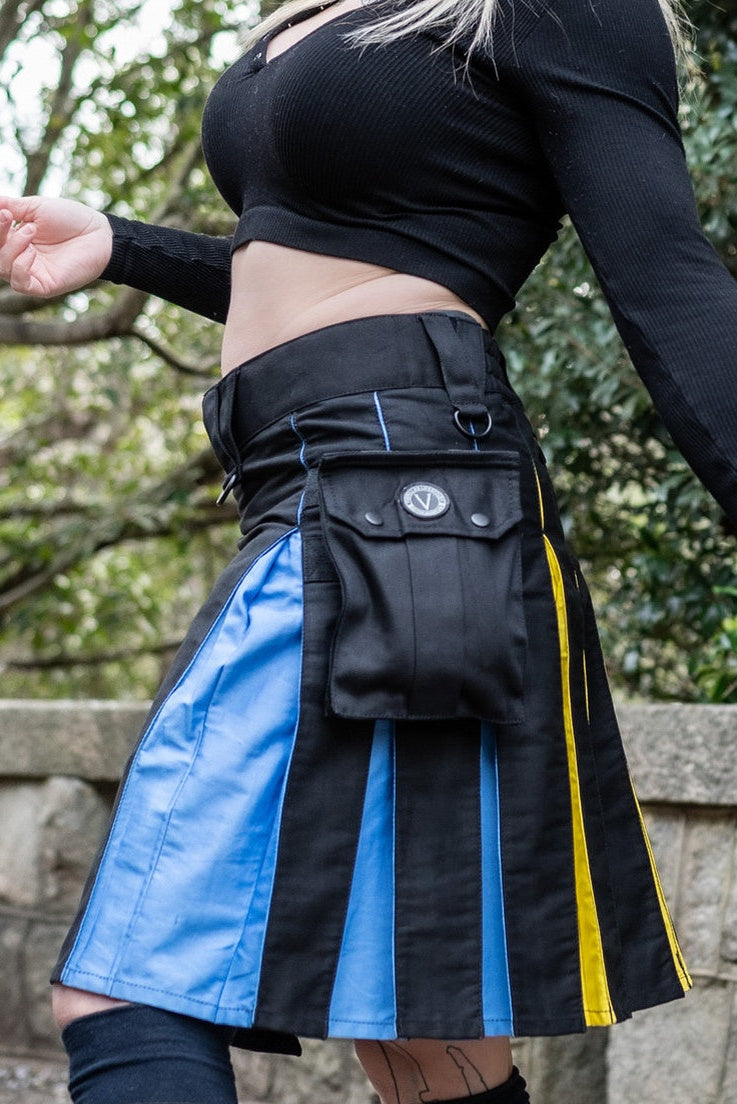 Person wearing a black and blue striped kilt with yellow accents outdoors.