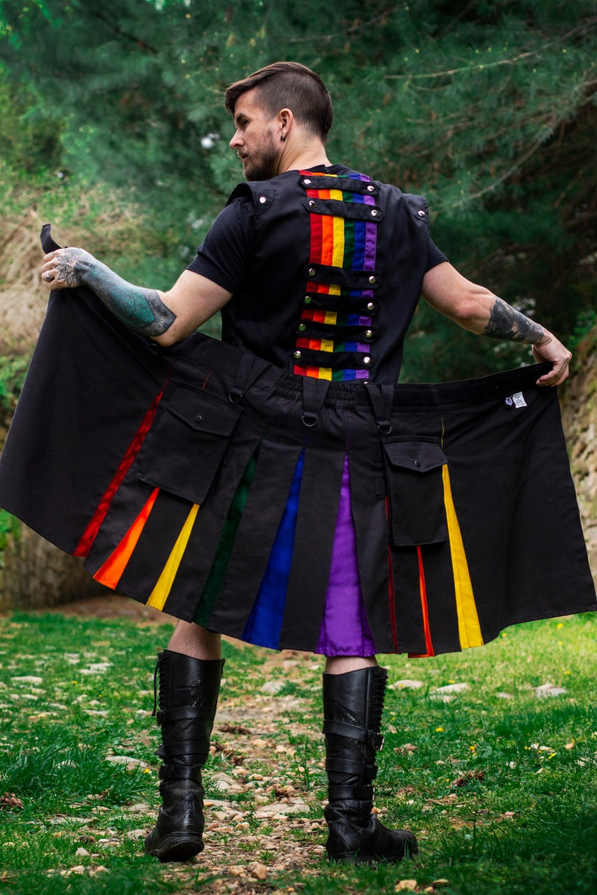 Person wearing a black kilt with rainbow accents outdoors.
