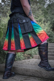 Person wearing an ombre rainbow kilt with black accents outdoors.