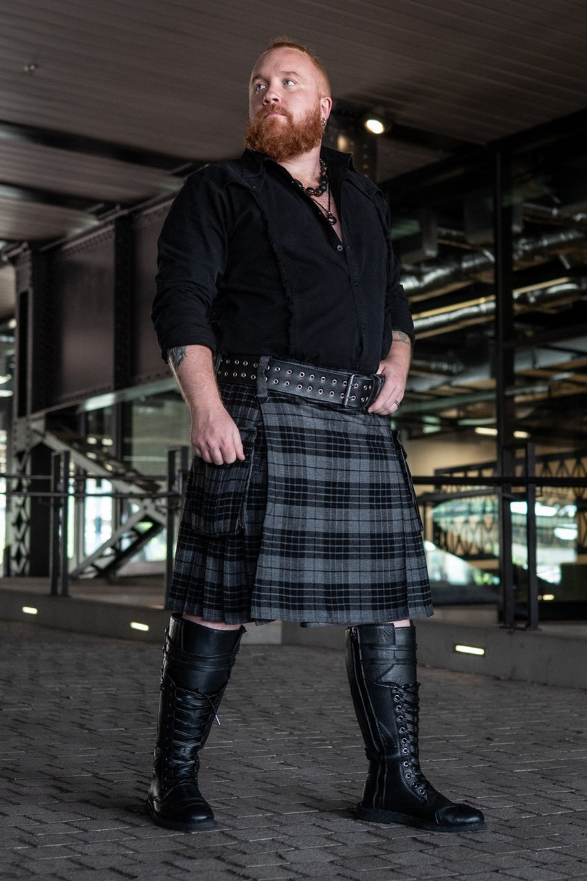 Man wearing a black shirt, gray kilt, and black knee-high boots in an urban setting.