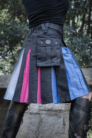 Close up of a person wearing a black kilt with blue, pink, and white side panels for trans pride. 