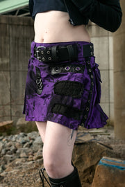 Close up of a person wearing a purple and black pleated mini kilt with black fabric details.